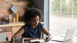 Smiling young multiracial businesswoman writing notes in notebook